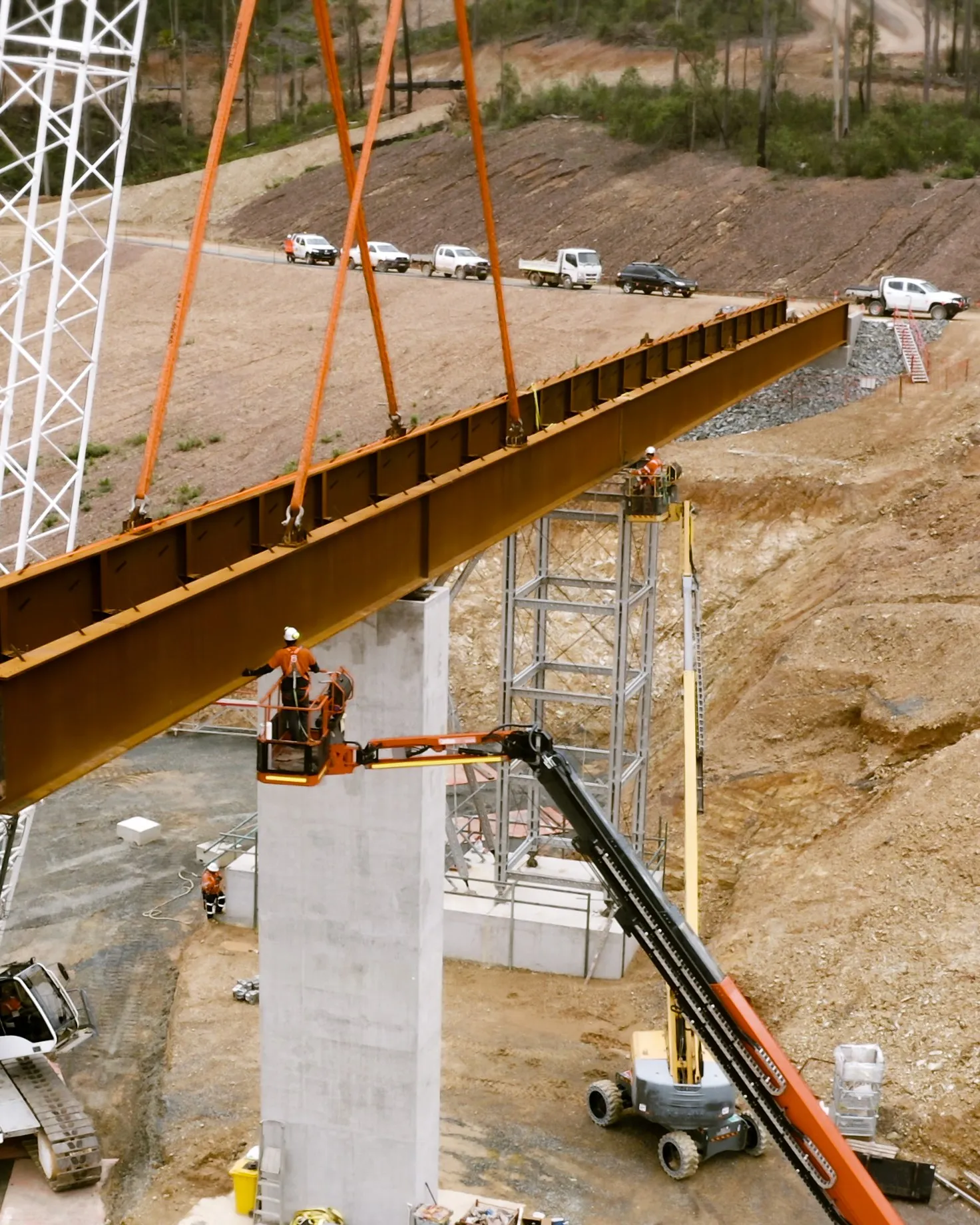 Crew in elevated work platforms guide a steel girder onto a concrete pier at the Eurobodalla Southern Storage Dam site