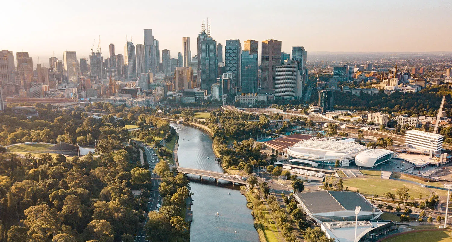 Aerial view of an Australian city and river, representing real assets anchored to structural demand
